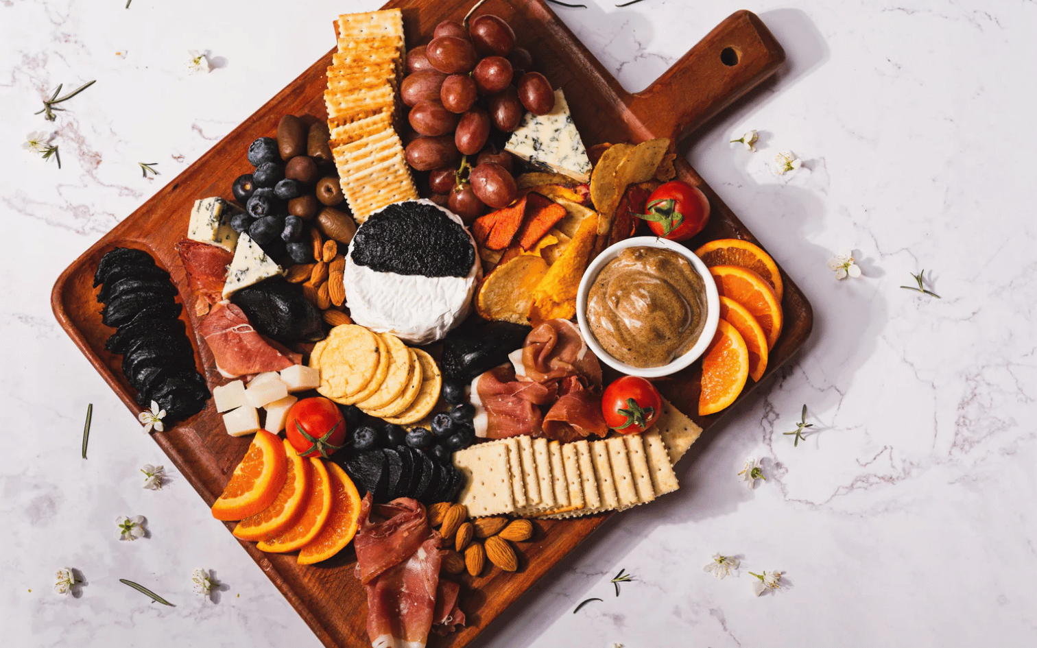 Tabla de aperitivos con ajo negro de la Patagonia Chilena, prosciutto, quesos y crackers